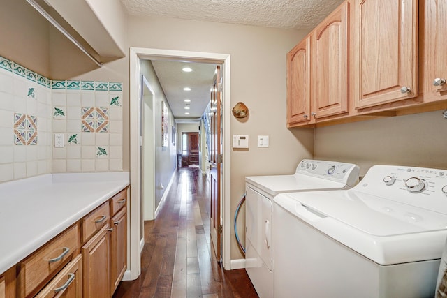 clothes washing area featuring washing machine and clothes dryer, cabinet space, a textured ceiling, recessed lighting, and dark wood-type flooring