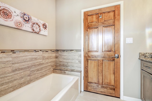 full bath featuring tile patterned floors, a garden tub, and vanity
