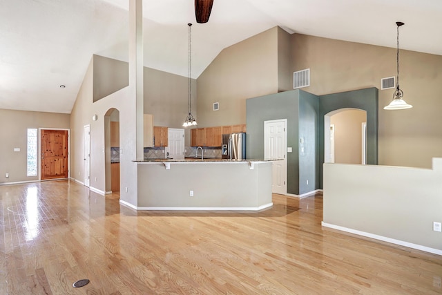 2703 Pueblo Grande Trl NW, Albuquerque, NM 87120 - unfurnished living room with visible vents, arched walkways, light wood-style floors, and high vaulted ceiling
