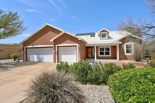 2703 Pueblo Grande Trl NW, Albuquerque, NM 87120 - view of front facade featuring stucco siding, covered porch, a garage, solar panels, and concrete driveway