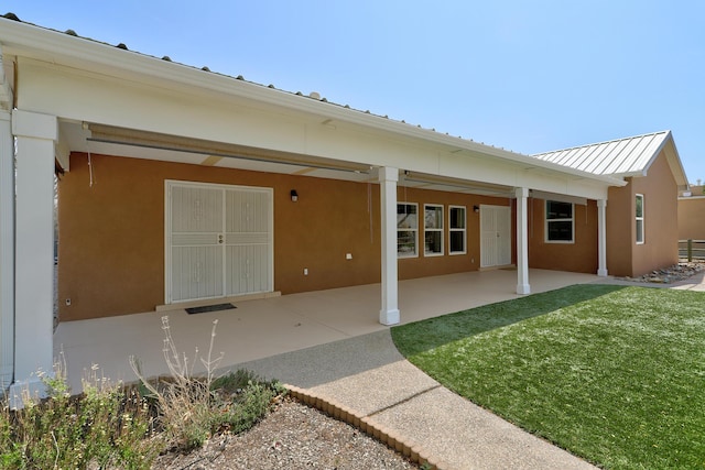 2703 Pueblo Grande Trl NW, Albuquerque, NM 87120 - back of house with metal roof, a yard, stucco siding, and a patio area