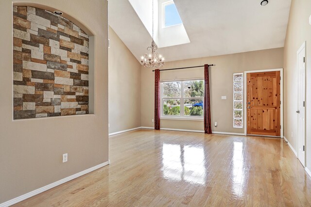 2703 Pueblo Grande Trl NW, Albuquerque, NM 87120 - unfurnished room with light wood finished floors, an inviting chandelier, high vaulted ceiling, baseboards, and a skylight
