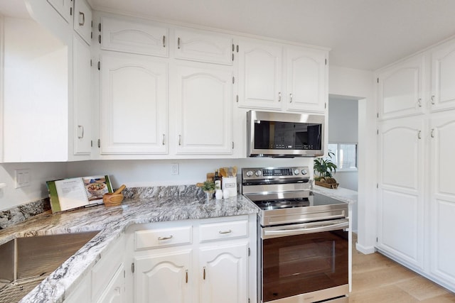 4500 Skyline Ct NE, Albuquerque, NM 87111 - kitchen featuring appliances with stainless steel finishes, white cabinets, light stone countertops, and light wood-style floors