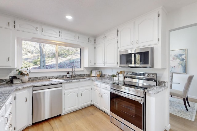 4500 Skyline Ct NE, Albuquerque, NM 87111 - kitchen with appliances with stainless steel finishes, light wood-style floors, white cabinetry, recessed lighting, and light stone counters