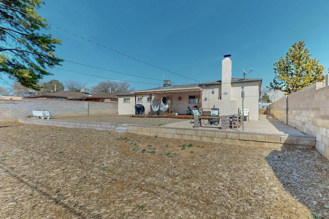 3501 Westerfeld Dr NE, Albuquerque, NM 87111 - back of property with a patio, a fenced backyard, and a chimney