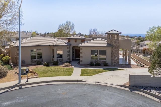 view of front of property with a tiled roof, stone siding, fence, stucco siding, and a front lawn
