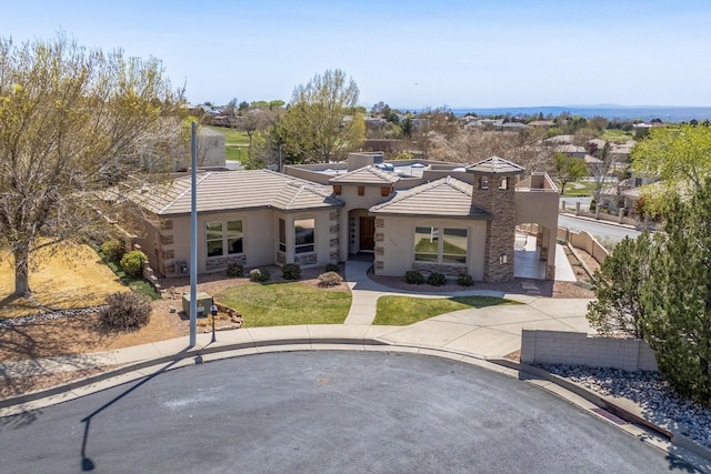 view of front of house with a tiled roof, a front lawn, stone siding, and stucco siding