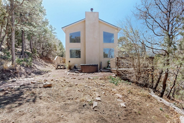 2 Cedar Hill Pl, Cedar Crest, NM 87008 - rear view of property featuring stucco siding, a hot tub, a chimney, and a wooden deck