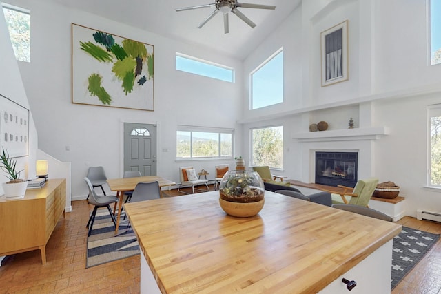 2 Cedar Hill Pl, Cedar Crest, NM 87008 - dining space featuring brick patterned floors, healthy amount of natural light, a high ceiling, a glass covered fireplace, and ceiling fan