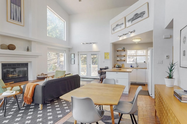 2 Cedar Hill Pl, Cedar Crest, NM 87008 - dining space featuring a high ceiling, a glass covered fireplace, brick patterned floors, and french doors
