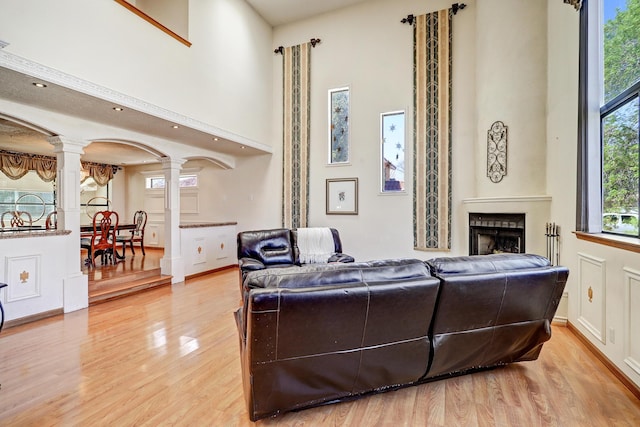 8300 R C Gorman Ave NE, Albuquerque, NM 87122 - living room featuring decorative columns, light wood finished floors, a towering ceiling, and a fireplace