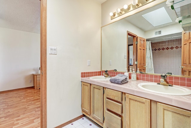 8300 R C Gorman Ave NE, Albuquerque, NM 87122 - bathroom featuring a skylight, double vanity, and a shower with curtain