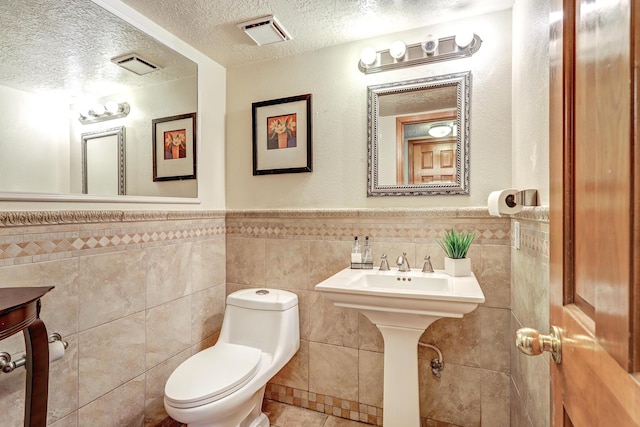 8300 R C Gorman Ave NE, Albuquerque, NM 87122 - bathroom with a textured ceiling, tile walls, a wainscoted wall, and tile patterned flooring