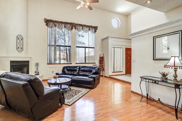 8300 R C Gorman Ave NE, Albuquerque, NM 87122 - living area featuring ceiling fan, a fireplace, light wood-style floors, and a towering ceiling