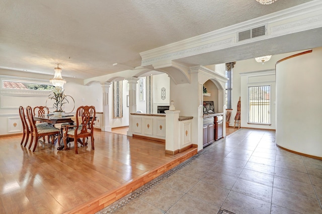 8300 R C Gorman Ave NE, Albuquerque, NM 87122 - dining area featuring a textured ceiling, decorative columns, a chandelier, light tile patterned flooring, and crown molding