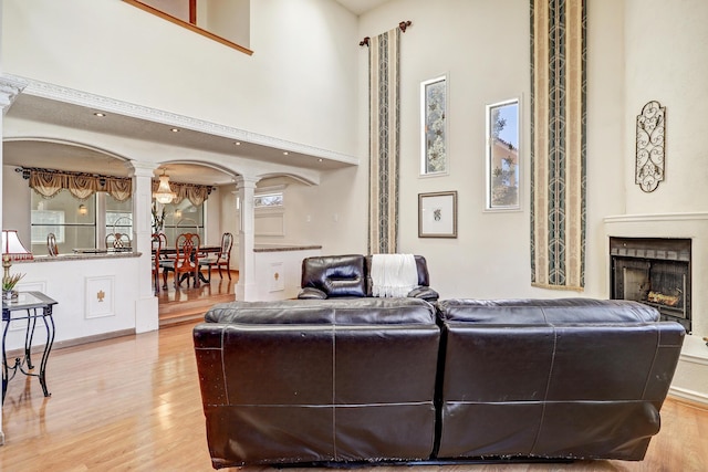 8300 R C Gorman Ave NE, Albuquerque, NM 87122 - living area featuring decorative columns, light wood-style floors, a high ceiling, and a fireplace