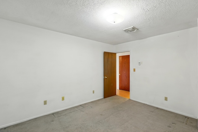 empty room featuring carpet flooring, visible vents, a textured ceiling, and baseboards