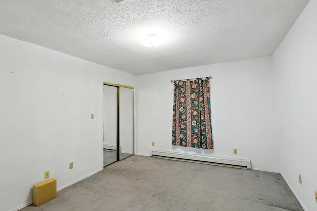unfurnished room featuring baseboard heating, a textured ceiling, baseboards, and carpet floors