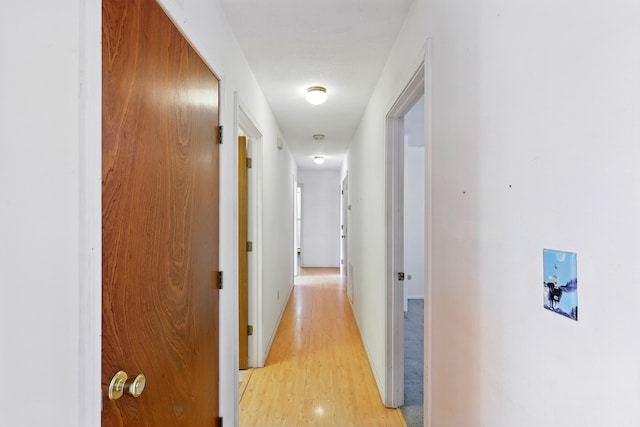 hall featuring light wood-style floors and baseboards