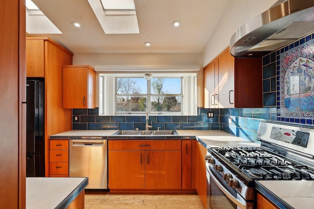 kitchen featuring tasteful backsplash, wall chimney exhaust hood, a sink, recessed lighting, and stainless steel appliances