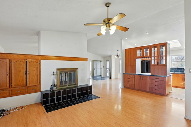 living area featuring high vaulted ceiling, light wood-style flooring, a ceiling fan, recessed lighting, and a tiled fireplace