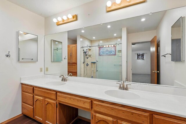 bathroom featuring double vanity, a sink, a stall shower, and wood finished floors