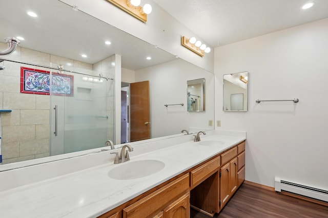 full bath featuring a stall shower, wood finished floors, a baseboard heating unit, and a sink