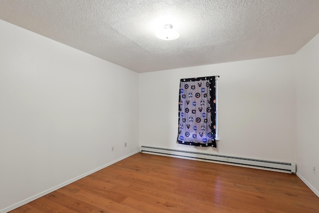 unfurnished room with a baseboard radiator, baseboards, and wood finished floors