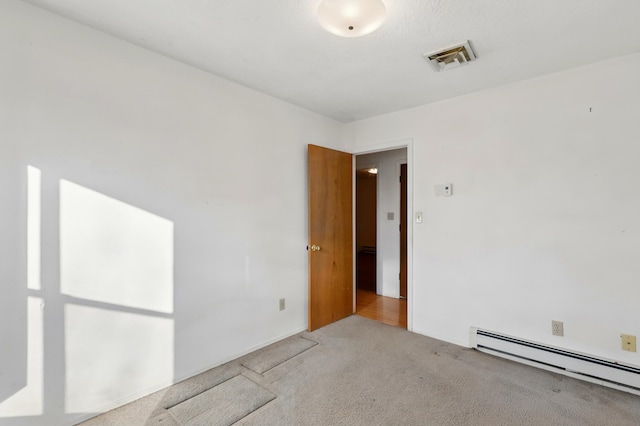 carpeted empty room with baseboard heating and visible vents