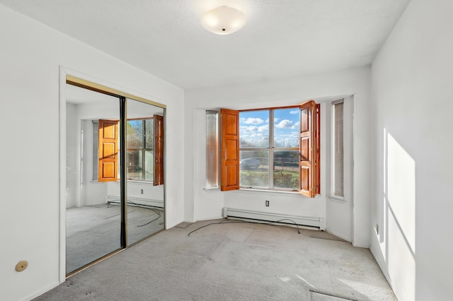 empty room featuring baseboards, a baseboard radiator, and light colored carpet