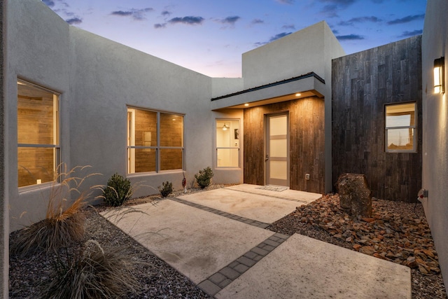 8023 Victoria Dr NW, Albuquerque, NM 87120 - exterior entry at dusk featuring a patio and stucco siding