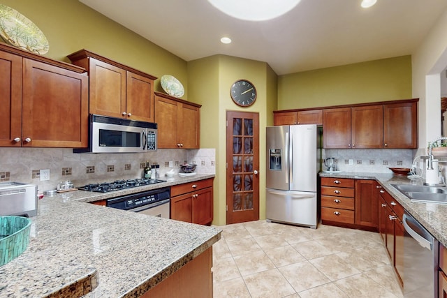 9840 Cameron St NW, Albuquerque, NM 87114 - kitchen featuring decorative backsplash, appliances with stainless steel finishes, brown cabinets, a sink, and light tile patterned floors