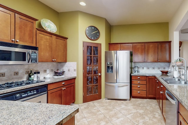 9840 Cameron St NW, Albuquerque, NM 87114 - kitchen featuring decorative backsplash, brown cabinets, a sink, light tile patterned floors, and stainless steel appliances