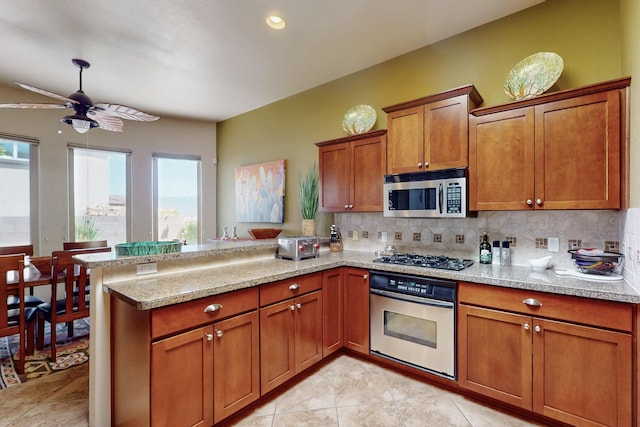 9840 Cameron St NW, Albuquerque, NM 87114 - kitchen with brown cabinetry, a peninsula, decorative backsplash, and appliances with stainless steel finishes