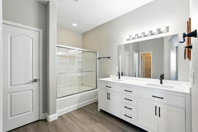 7327 Hearthstone Rd NW, Albuquerque, NM 87114 - full bathroom with combined bath / shower with glass door, double vanity, and wood finished floors