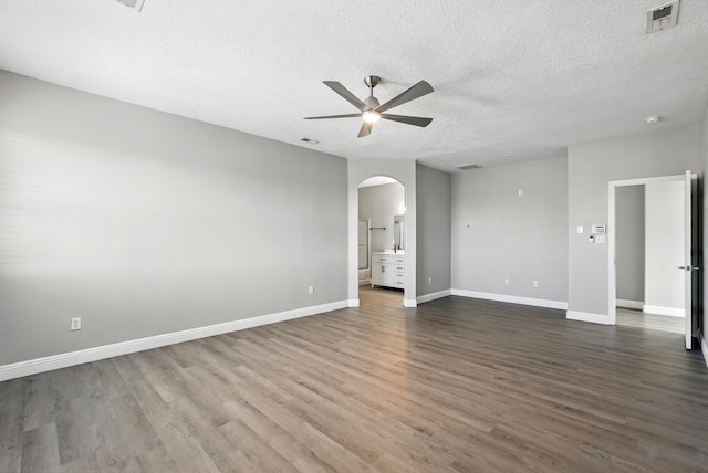 7327 Hearthstone Rd NW, Albuquerque, NM 87114 - unfurnished room with a ceiling fan, arched walkways, dark wood finished floors, a textured ceiling, and baseboards