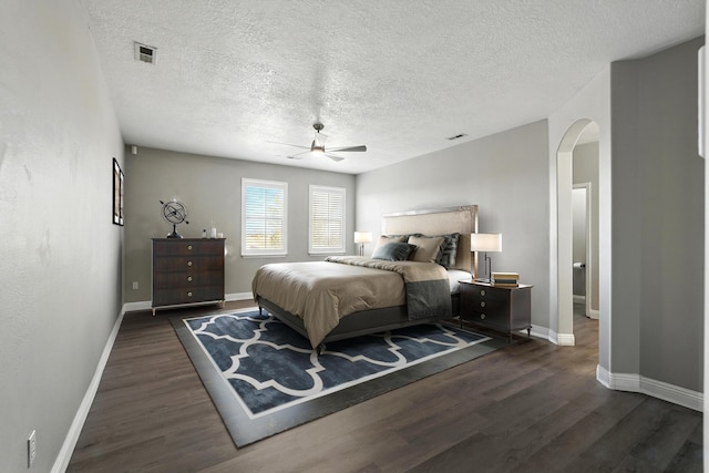 7327 Hearthstone Rd NW, Albuquerque, NM 87114 - bedroom featuring arched walkways, dark wood-style floors, baseboards, a textured ceiling, and ceiling fan