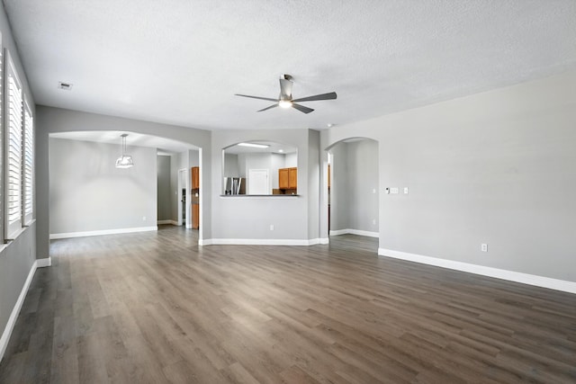7327 Hearthstone Rd NW, Albuquerque, NM 87114 - unfurnished living room with ceiling fan, arched walkways, dark wood-style flooring, a textured ceiling, and baseboards