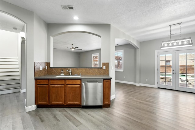 7327 Hearthstone Rd NW, Albuquerque, NM 87114 - kitchen with stainless steel dishwasher, a sink, arched walkways, light wood-type flooring, and decorative backsplash