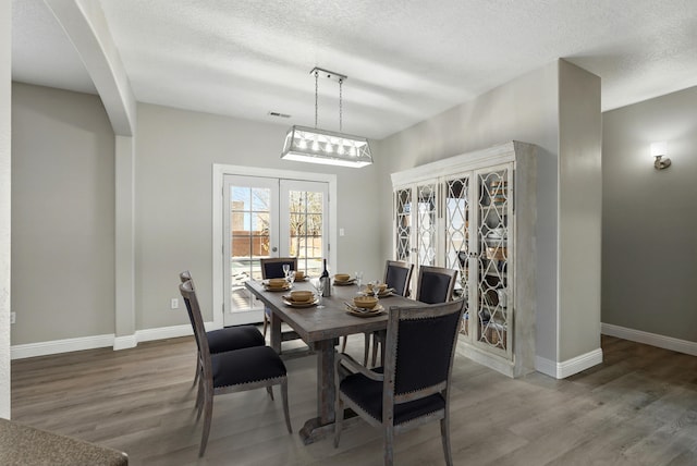 7327 Hearthstone Rd NW, Albuquerque, NM 87114 - dining room with wood finished floors, arched walkways, baseboards, and a textured ceiling