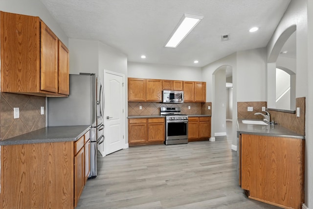 7327 Hearthstone Rd NW, Albuquerque, NM 87114 - kitchen featuring appliances with stainless steel finishes, a sink, decorative backsplash, light wood-type flooring, and recessed lighting