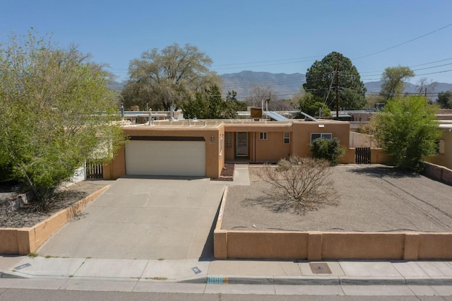 southwest-style home featuring an attached garage, a mountain view, stucco siding, and concrete driveway