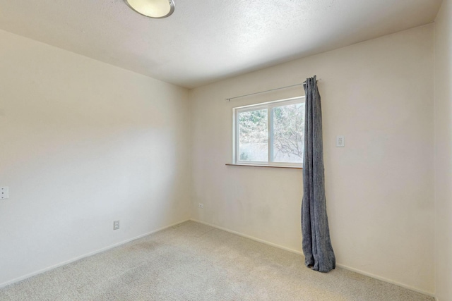 empty room featuring baseboards and light colored carpet
