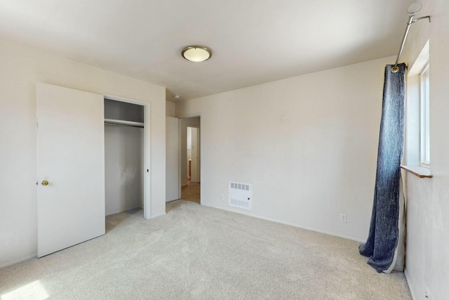 unfurnished bedroom featuring visible vents, light carpet, and a closet
