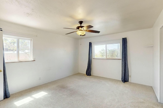 unfurnished room with ceiling fan, light colored carpet, and a healthy amount of sunlight