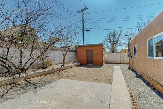 view of yard featuring an outdoor structure, a fenced backyard, a patio area, and a shed