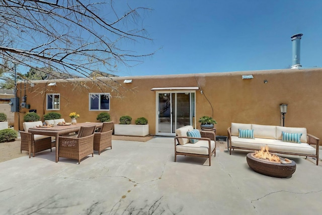 rear view of house featuring outdoor dining area, an outdoor living space with a fire pit, a patio, and stucco siding