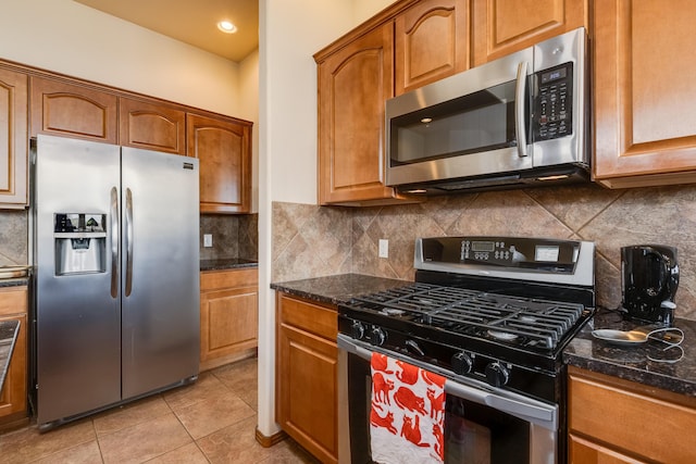4701 Mi Cordelia Dr NW, Albuquerque, NM 87120 - kitchen with appliances with stainless steel finishes, light tile patterned floors, tasteful backsplash, brown cabinets, and dark stone countertops