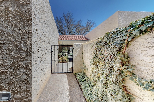 exterior space with a tiled roof, a gate, and stucco siding