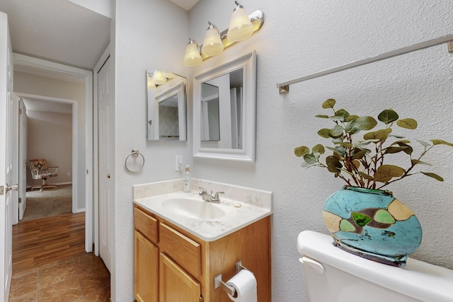 bathroom with toilet, wood finished floors, and vanity